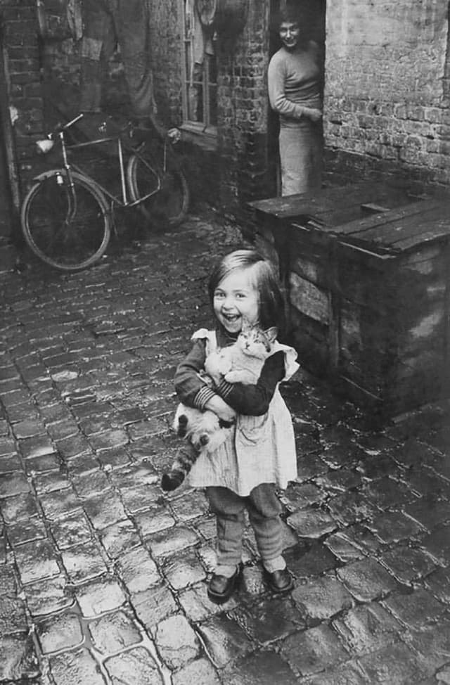 Original photo of girl with cat in cobblestone alley